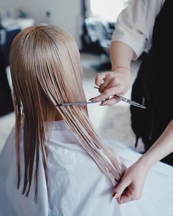 Blonde klant krijgt een knipbeurt in een lichte, moderne kapsalon